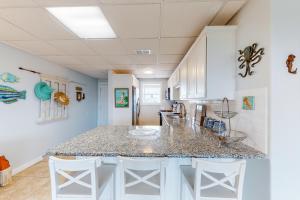 a kitchen with a counter top and white cabinets at Seaside Pearl in Mustang Beach