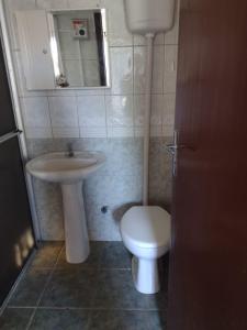 a bathroom with a sink and a toilet and a mirror at Scotti's Suítes in Capão da Canoa