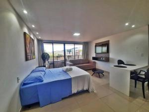 a bedroom with a blue bed and a living room at GoldFlat in João Pessoa