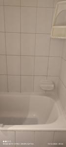 a white bath tub in a white tiled bathroom at Departamento Full 3D 2B Cerca de Playas en Arica in Arica