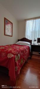 a bedroom with a bed with a red blanket and a piano at Departamento Full 3D 2B Cerca de Playas en Arica in Arica