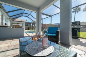 a glass table with a bottle and two glasses of wine at Serene Seaside Retreat - Dog friendly - 2BR Townhouse with Heated Pool Steps to Paradise Beach! in Melbourne