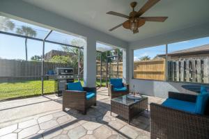 a patio with blue chairs and a ceiling fan at Serene Seaside Retreat - Dog friendly - 2BR Townhouse with Heated Pool Steps to Paradise Beach! in Melbourne