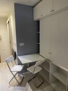 cocina con 2 sillas, mesa y armarios en Lovely Loft Bernabéu Madrid en Madrid