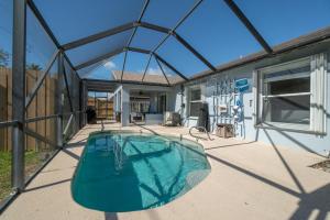 a swimming pool with a glass roof on a patio at Oceanview Haven - 2BR Beach House with Patio Heated Pool Steps from Paradise Beach Park! in Melbourne