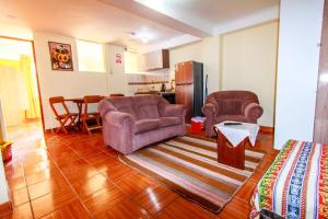 a living room with two chairs and a kitchen at T'ika Guest House in Cusco