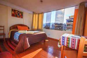 a bedroom with a bed and a large window at T'ika Guest House in Cusco