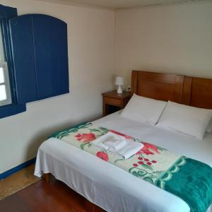 een slaapkamer met een bed met een deken erop bij Hotel Barroco Mineiro in Ouro Preto