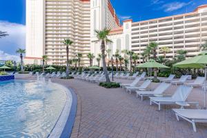 a row of white lounge chairs next to a pool at Luxurious 4 Bedroom Condo! Gulf Views! Sleeps 10 & Easy Beach Access! by Dolce Vita Getaways PCB in Panama City Beach