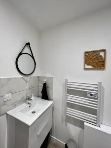 een witte badkamer met een wastafel en een spiegel bij L'Orangeraie in Brioude