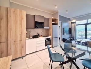a kitchen and dining room with a glass table and chairs at 11 Floors in the Sky - Luxurious 1 Bedroom in Pretoria