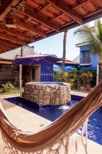 a hammock on a patio next to a swimming pool at Pousada Canto Azul Guarujá in Guarujá