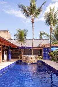 a swimming pool with palm trees in front of a house at Pousada Canto Azul Guarujá in Guarujá