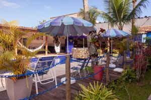 a patio with chairs and an umbrella and palm trees at Pousada Canto Azul Guarujá in Guarujá