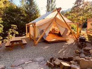 a large tent with a picnic table and a bench at Umpqua's Last Resort - Wilderness Cabins, RV Park & Glamping in Idleyld Park