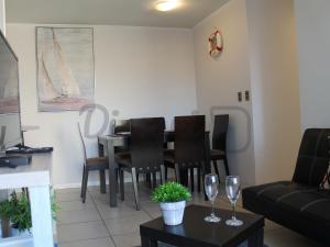 una sala de estar con mesa, sillas y copas de vino en Departamento Av del Mar La Serena Disegni 02, en Coquimbo