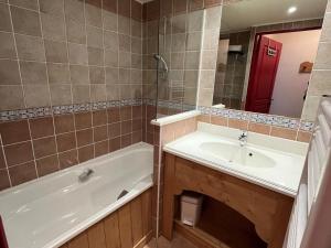 a bathroom with a tub and a sink and a mirror at Appartement Lanslebourg-Mont-Cenis, 3 pièces, 6 personnes - FR-1-508-256 in Lanslebourg-Mont-Cenis