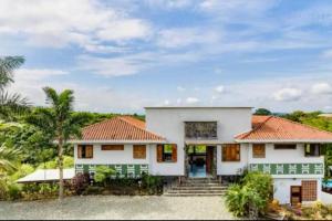 a white house with a palm tree at Casa Campestre Montenegro cerca al Parque del Café con piscina privada in Montenegro