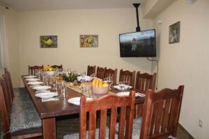 a long table with chairs and a television in a room at Къща за гости - Вила Сидона in Banya