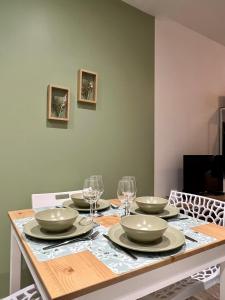 una mesa con cuatro platos y copas de vino. en L'Oliveraie en Brioude