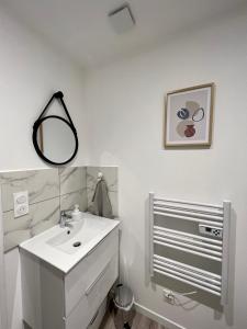 a white bathroom with a sink and a mirror at L'Oliveraie in Brioude