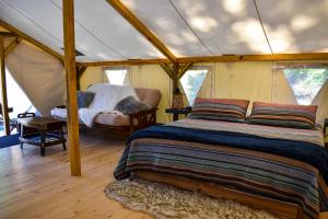 a bedroom in a tent with a bed and a couch at Umpqua's Last Resort - Wilderness Cabins, RV Park & Glamping in Idleyld Park