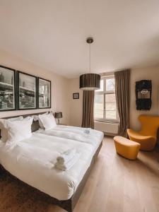 a bedroom with a large white bed and a yellow chair at Château Charles in Pepinster