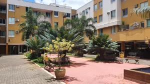 um pátio com bancos e palmeiras em frente a um edifício em Ed. Boulevar Antares II em Brasília