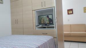 1 dormitorio con TV de pantalla plana en la pared en Ed. Boulevar Antares II en Brasilia