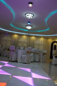 شاليهات دي لا كروز في مكة المكرمة: غرفة بها طاولات وكراسي بيضاء وأضواء أرجوانية