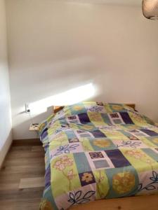 Una cama con edredón en un dormitorio en Au Talhorn chez Marc, en Fellering