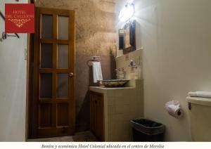 a bathroom with a sink and a toilet and a door at Hotel Morelia Callejón in Morelia