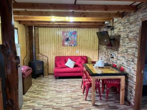sala de estar con sofá rojo y mesa en Cabañas "El Cazador" en Futaleufú