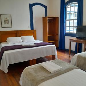 um quarto de hotel com duas camas e uma televisão em Hotel Barroco Mineiro em Ouro Preto