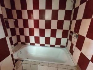 uma banheira na casa de banho com uma parede xadrez em Hostal Maria Mercedes em Baños