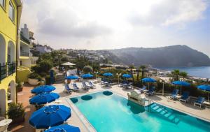 a swimming pool with blue umbrellas and chairs at Hotel Capizzo in Ischia