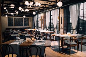 a dining room with tables and chairs and windows at Forest 1961 Boutique Hotel & Restaurant in Vanadzor