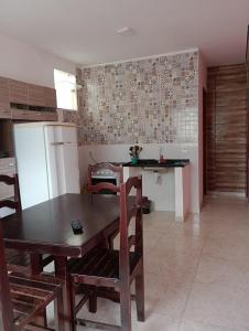 eine Küche mit einem Tisch und Stühlen sowie einem Kühlschrank in der Unterkunft Casa enteira con piscina compartilhada in Búzios