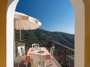 uma mesa com cadeiras e um guarda-sol numa varanda em Agriturismo IL POGGIO DI VASIA CITR00864-AGR-0001 em Vasia