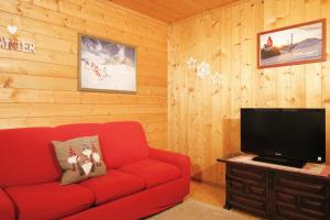 sala de estar con sofá rojo y TV de pantalla plana en CASA PAMPEAGO - Sulle piste da sci del Latemar en Tesero