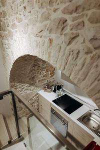 uma cozinha com uma parede de pedra e um lavatório em Amiura B&B em Corato