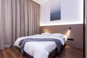 a bedroom with a large bed with white sheets at cohost I New Bastėja Life Apartments w-Garage Prkg & Self Check-in in Vilnius