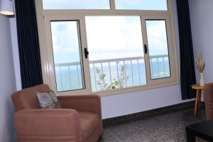 a living room with a chair and two windows at Nour 1 Sea View Apartment in Alexandria