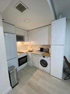 cocina con armarios blancos y lavadora en Bausa 19 en Madrid