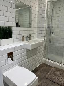 een witte badkamer met een wastafel en een douche bij Elegant & Cozy, Gold Decor Apartment, B1 in Birmingham