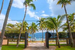 a view of the beach from a resort with palm trees at Vila M Suítes ᵇʸ ᴬᴸᴱᴮᴬᴴᴸᴵ in Ilhabela