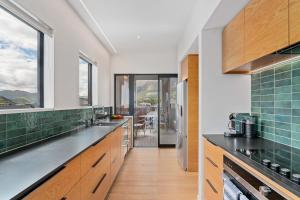 a kitchen with wooden cabinets and green tiles at Stay Soudley @ Jack's in Frankton Wharf