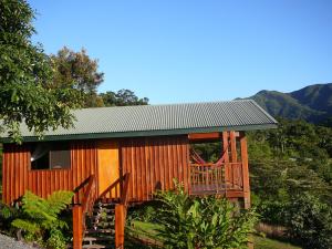 a cabin with a deck and mountains in the background at Coral Sea Views in Diwan