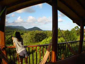 une femme debout sur un balcon qui prend une photo des montagnes dans l'établissement Coral Sea Views, à Diwan