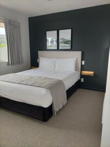 a bedroom with a large bed with two windows at Boutique Motel in Nelson